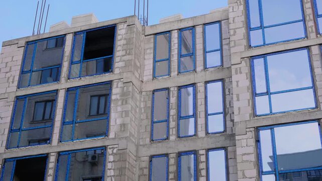 Building Facade Windows Installation. Facing Building Construction Site. Monolithic Concrete Frame of Apartment Building, Construction with Ready-Made Facade Aerated Concrete Blocks