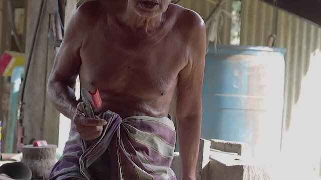 Old man rubber tapper shirtless worker rural traditional knife manual labor elderly man village workshop rubber tapping craft Asian rural life