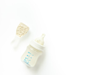 Powdered infant formula in a scoop and baby milk bottle on white background. Top view.