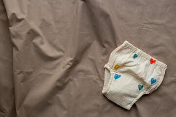 Baby cotton diaper pantie on beige sheet, top view. Eco friendly cloth