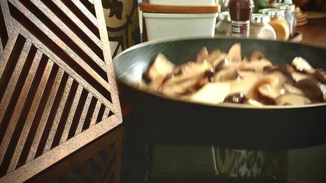 Dynamic shot of gourmet mushrooms being tossed in a hot frying pan. Professional chef technique for saut&eacute;ing king oyster and shiitake mushrooms in a cozy home kitchen. Motion blur, cooking action.