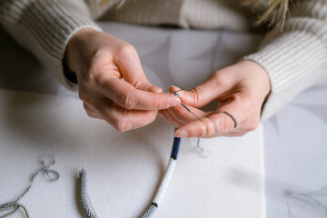 Female hands making handmade beaded jewelry