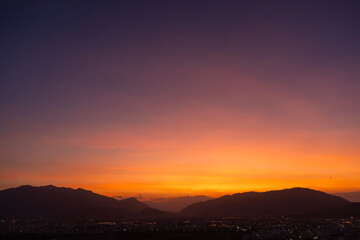 Bright sunset over the silhouette mountains at evening time.