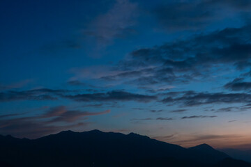Bright sunset over the silhouette mountains at evening time.