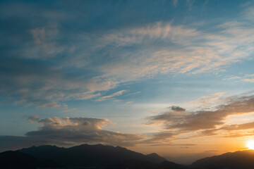 Bright sunset over the silhouette mountains at evening time.
