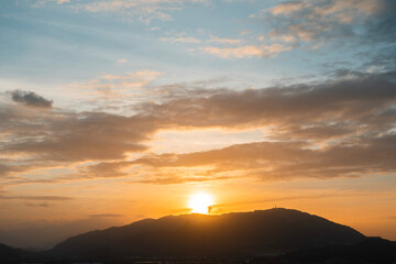 Bright sunset over the silhouette mountains at evening time.