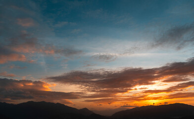 Bright sunset over the silhouette mountains at evening time.