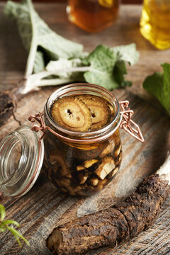 Making homemade herbal tincture from fresh wild burdock root in a jar