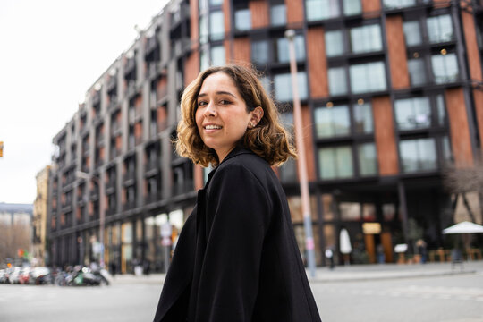 Woman in urban setting smiling confidently
