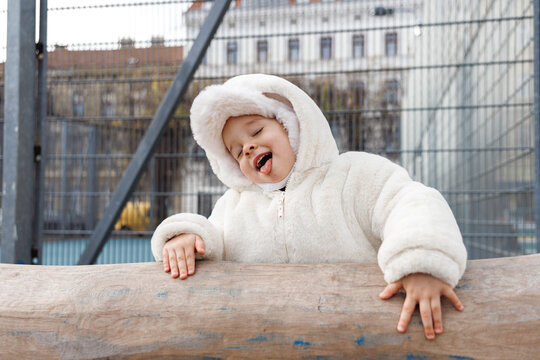 Happy child in warm coat with tongue out at playground