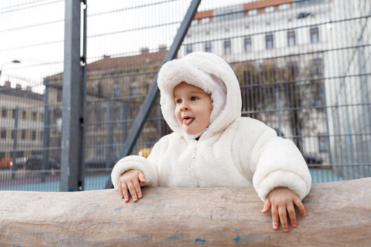 Adorable child in a white coat at outdoor play area