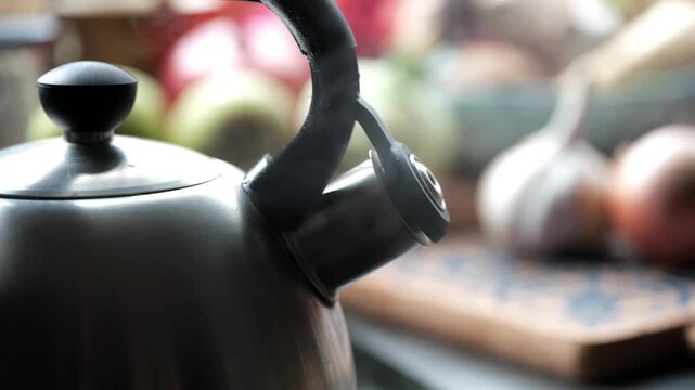Whistling Kettle Boiling Water with Steam, close-up 4K shot of a metal kettle with a whistle releasing steam while boiling on a stove. Concept of hot water preparation, cooking, home routine, kitchen 