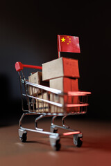Chinese products packed in boxes stacked on shopping cart with Chinese flag
