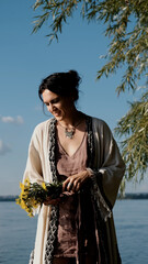 Beautiful brunette in boho style holds a bouquet of yellow flowers in her hands