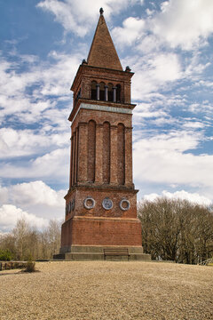 Historic brick tower located on Himmelbjerget hill near Silkeborg in Denmark, rising prominently against a dramatic cloudy sky. Monument stands on an open landscape, surrounded by trees and natural