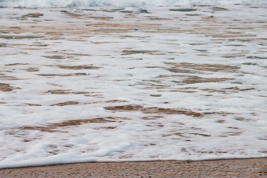sea foam on sand, breaking waves