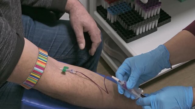Medical blood collections procedure showing only nurses gloved hand and patient arm. Preventive heals check and blood donation concept.
