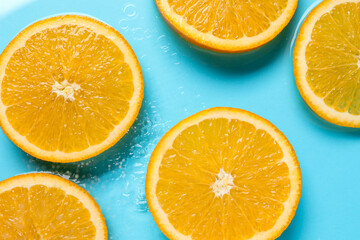 Fototapeta premium Orange slices in water on light blue background, flat lay