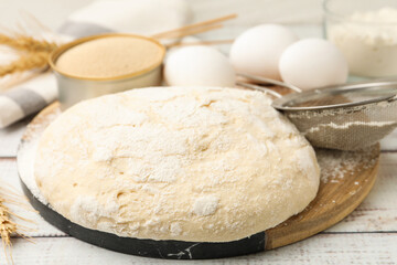 Fototapeta premium Yeast dough, ingredients and sieve on white wooden table, closeup