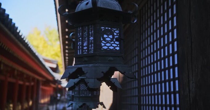 Long line of old, metal lanterns hanging from ancient Japanese roof tops - steady cam closeup