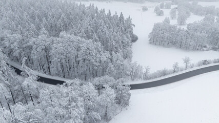 Landstra&szlig;e durch verschneiten Wald Drohnenaufnahme