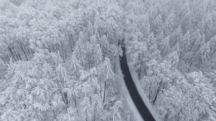 Landstra&szlig;e durch verschneiten Wald Drohnenaufnahme