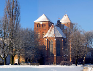 Historic brick church in Ketrzyn during winter. Gothic architecture landmark in Poland under a blue sky.