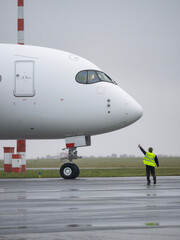 Airport ground crew worker giving thumbs up signal to airplane pilot before departure