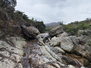 Panoramic view of a rocky stream landscape in a mountain valley under a cloudy sky
