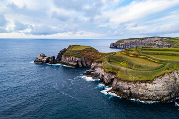 Headland covered with green vegetation and surrounded by rugged volcanic cliffs, Azores Islands