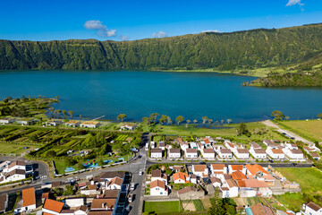 Aerial view of white houses in Sete Cidades by lake shore surrounded by lush crater landscape
