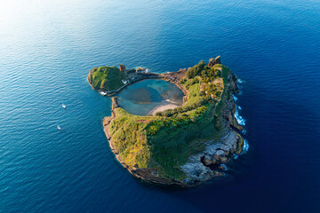 Aerial drone shot rocky volcanic island with crater lake in front of the Sao Miguel island, Azores