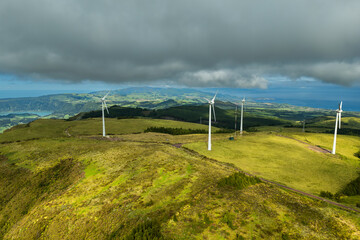 Wind turbines across green island landscape of Azores under Atlantic clouds. Renewable energy supporting sustainable island power systems