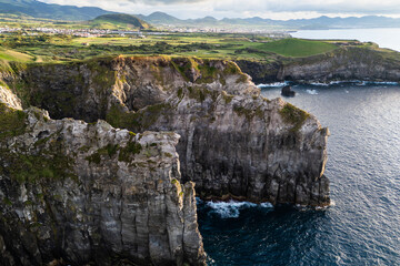 Dramatic volcanic cliffs and Atlantic ocean the rugged shoreline of Cape Cintrao at sunset. Azores aerial drone shot