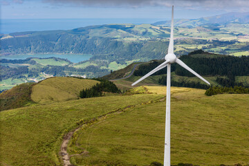 Wind turbine on Atlantic islands of Azores with green hills. Renewable electricity for isolated regions