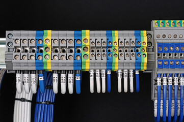 Electrical terminals with connected insulated wires with metal lugs. It is installed on a metal mounting rod in the electrical panel. 