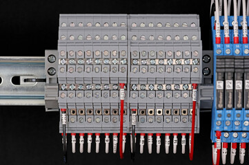 Electrical terminals with connected insulated wires with metal lugs. It is installed on a metal mounting rod in the electrical panel. 