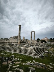 Ancient Temple of Apollo ruins in Didim, Turkey, under dramatic cloudy sky and archaeological landscape.