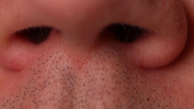 An extreme macro close-up focusing on the lower part of a human nose and the upper lip (philtrum) area.