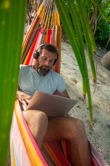 Digital Nomad Working on Laptop in Hammock on Tropical Beach