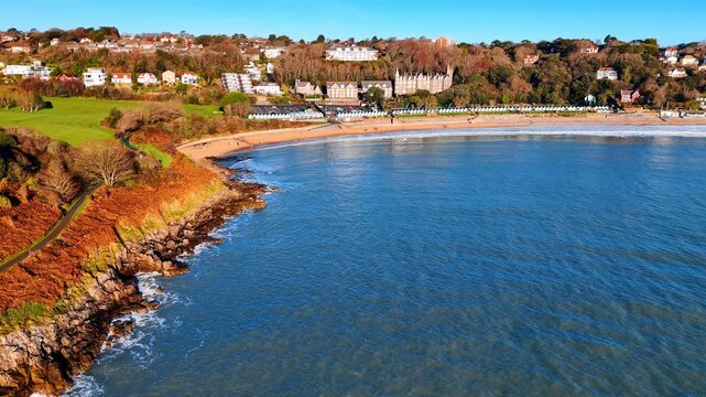 Aerial view of Langland Bay beach and seafront buildings. High angle perspective of a sandy beach, turquoise water, and Victorian style architecture along the coast.