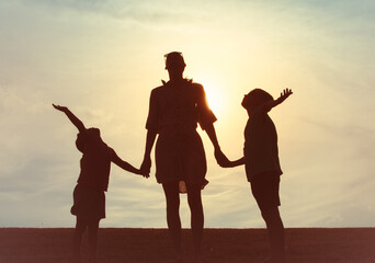 Fototapeta premium Mother and Children Silhouette at Sunset Holding Hands 