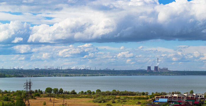 Power plant by lake under bright beautiful clouds
