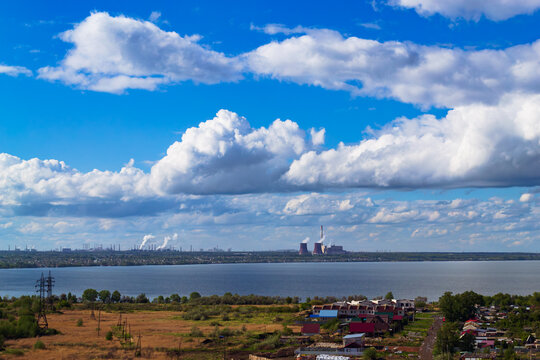 Power plant by lake under bright beautiful clouds