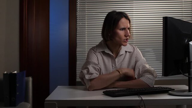 Frustrated businesswoman reacting angrily at work, expressing stress and burnout by throwing a computer keyboard across her desk in an office environment