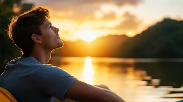 Young man relaxes on kayak, breathing fresh air and admiring beautiful sunset over tranquil lake