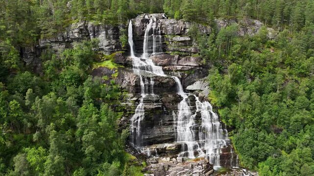 backward drone flight, reveal water and rocks of a big waterfall in Norway. Amazing nature, water falling from mountain, plants are growing on the rocks. Pure water, pristine nature. Tvindefossen. For