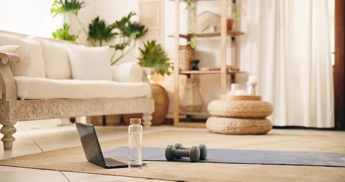 Laptop, dumbbells and water on floor of living room, fitness training gear and online workout class. Exercise mat, weights and bottle with pc to live stream in home, routine setup and tutorial video