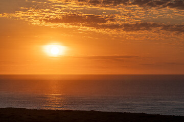 Amazing sunset sky with small scattered clouds creating vibrant colors over serene landscape