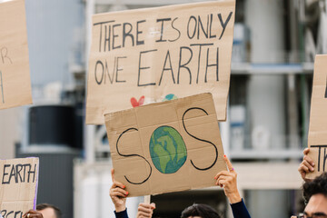 Activists raising cardboard signs during a public demonstration, advocating for environmental protection and calling attention to the urgent climate crisis